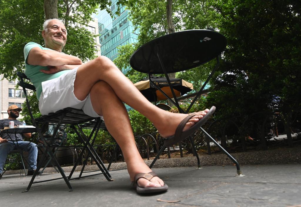 Man sitting at park table wears flip flops.