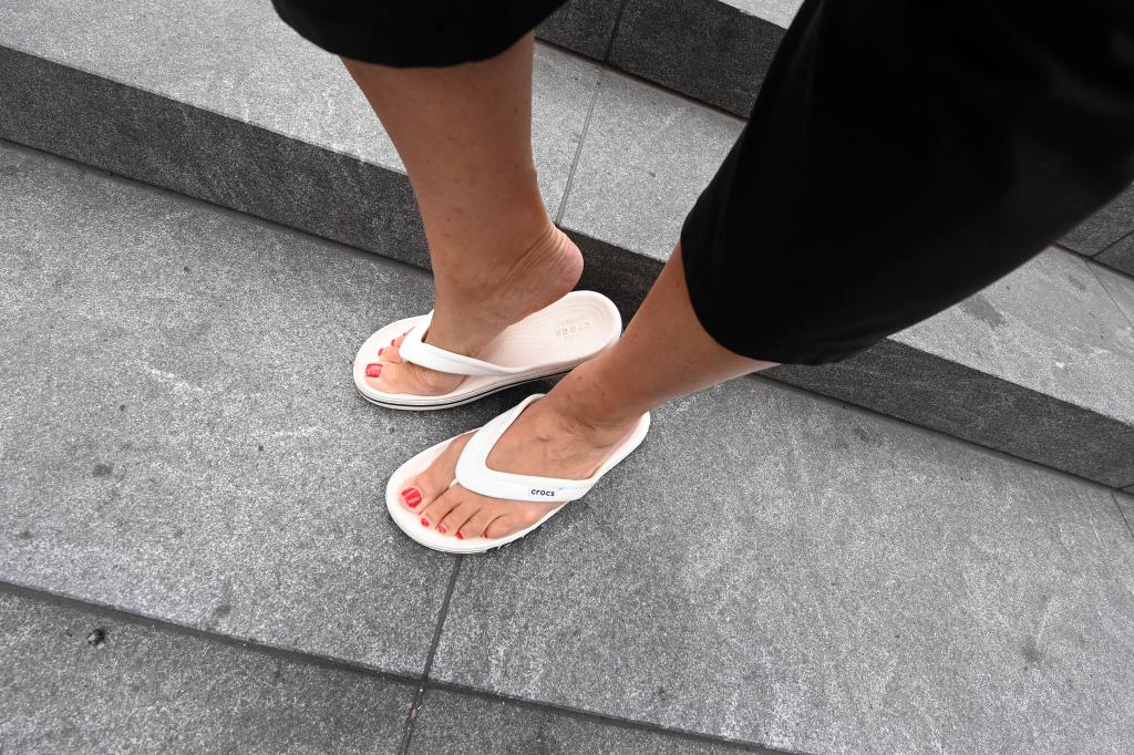 Woman with white flip flops poses on a New York City street. 