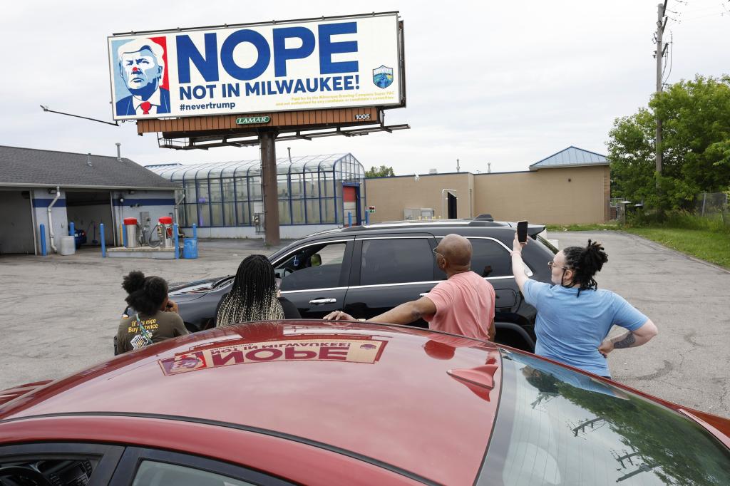 People in front of a billboard in opposition to Trump