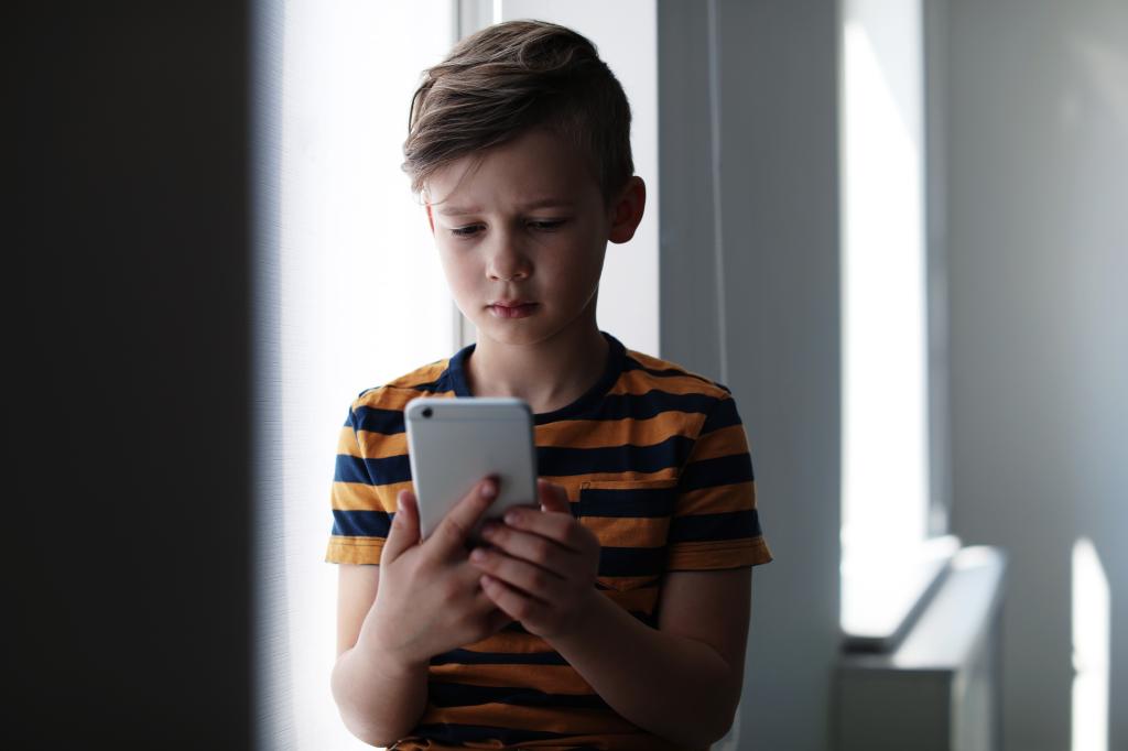 A young boy holds a smartphone.