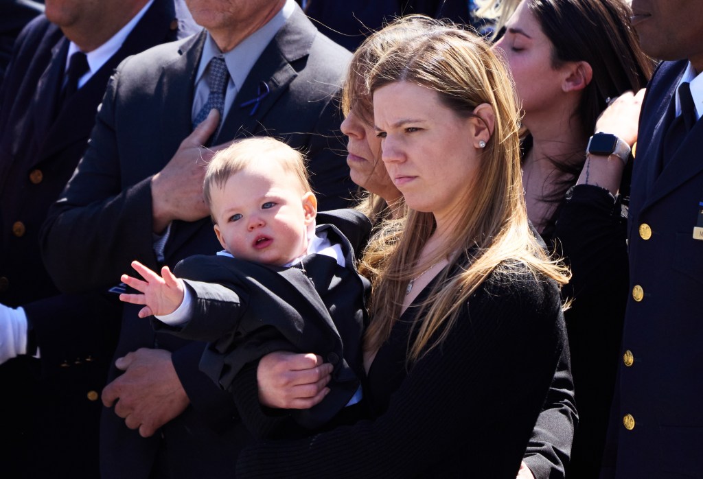 The baby appears to reach out to his father's casket as it's carried away.