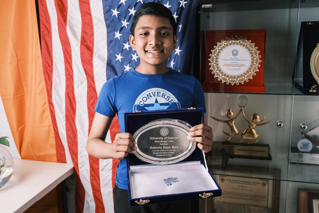 12-year-old prodigy, Suborno Issac Bari, holding a silver oval object in front of a flag, with an inspirational quote about goals