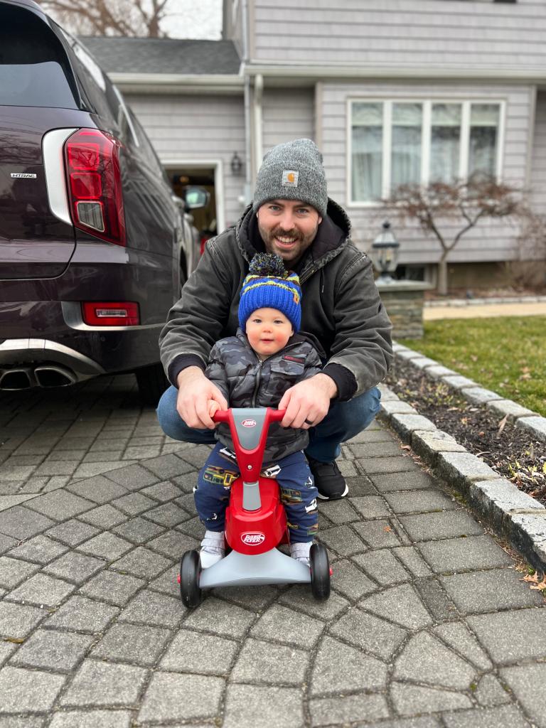 Jonathan Diller and his son pose with a child's tricycle.