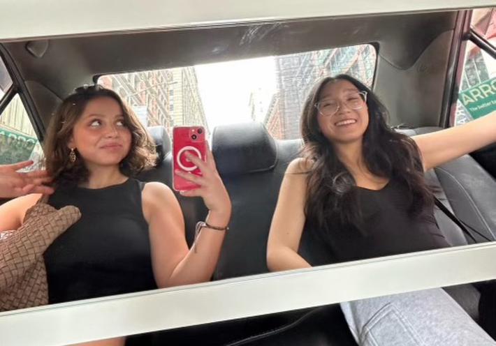 Agapov, left, holding a red cell phone and taking a selfie in the back seat of a car with Fung, right