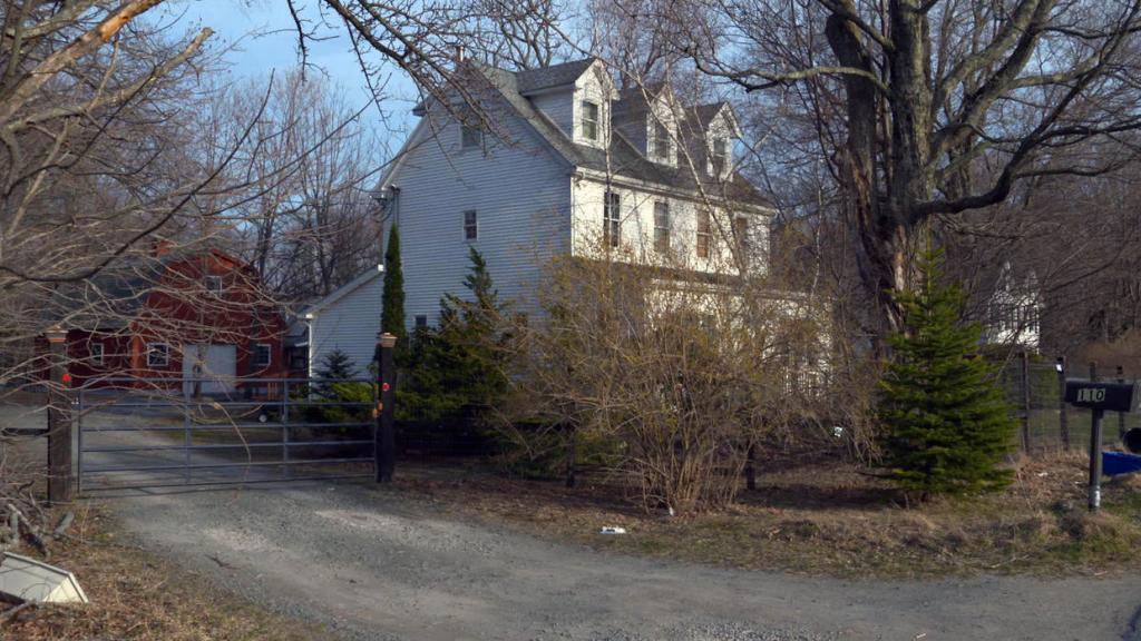 A secluded house with a gate and trees in the Catskills Mountains, known as Anne Hamilton-Byrne's hideaway