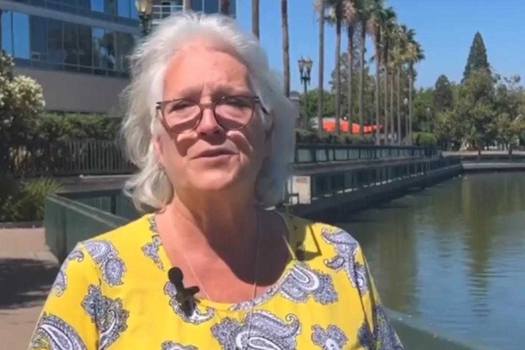 Karen cammer looking at the camera, with grey hair, glasses and a yellow and greyt op, outside with palm trees behind her