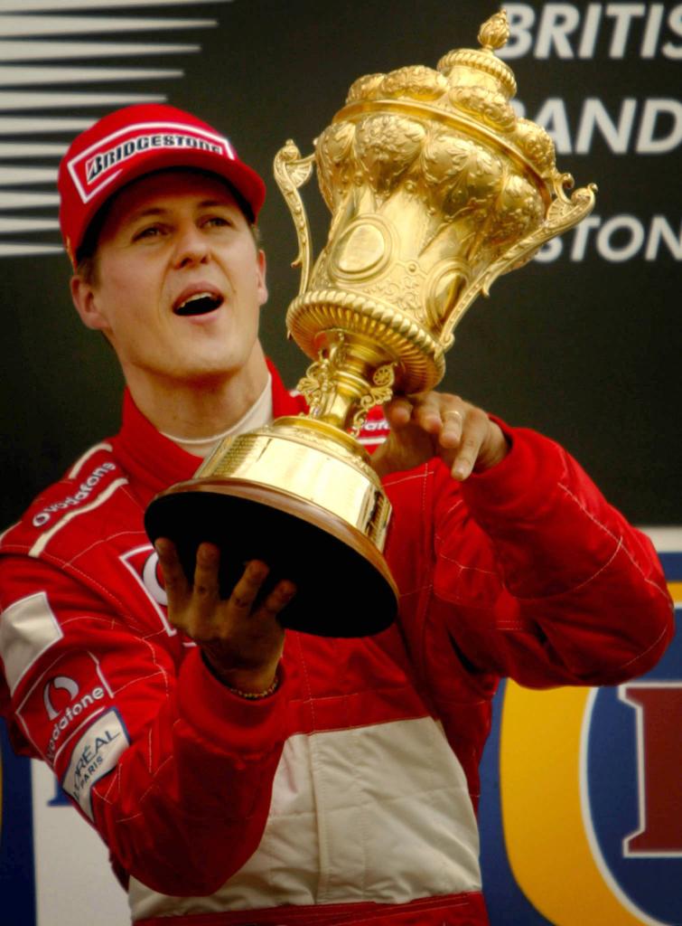 Ferrari's German driver Michael Schumacher lifts the trophy after wining the British Grand Prix at Silverstone on July 7, 2002.  