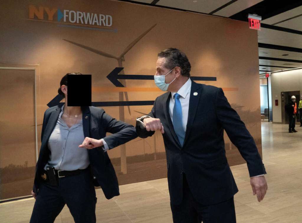 Gov. Andrew M. Cuomo bumps elbows with a 30-year-old female trooper at an event at Penn Station in Manhattan in December 2020. The now-former governor has been accused of sexually harassing the trooper after he directed members of his Protective Services Detail to offer her a job on the unit in 2017.