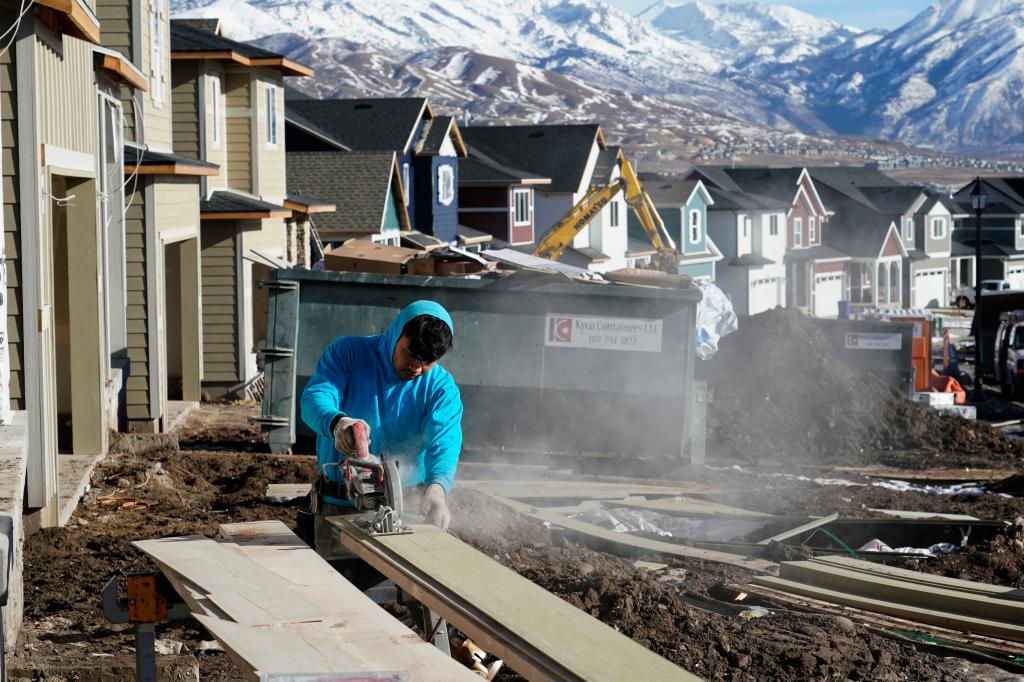 A worker prepares siding to install on a single family home under construction in Lehi, Utah