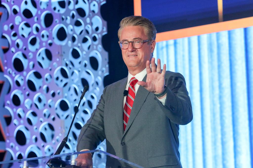 Joe Scarborough, host of Morning Joe on MSNBC, giving a keynote speech at the CRE Finance Council mid-year Annual Conference in New York City, seen waving from the podium.