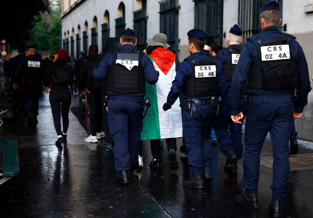 A man wearing the flag of Palestine is pictured with police officers outside the stadium after the match on July 27, 2024.