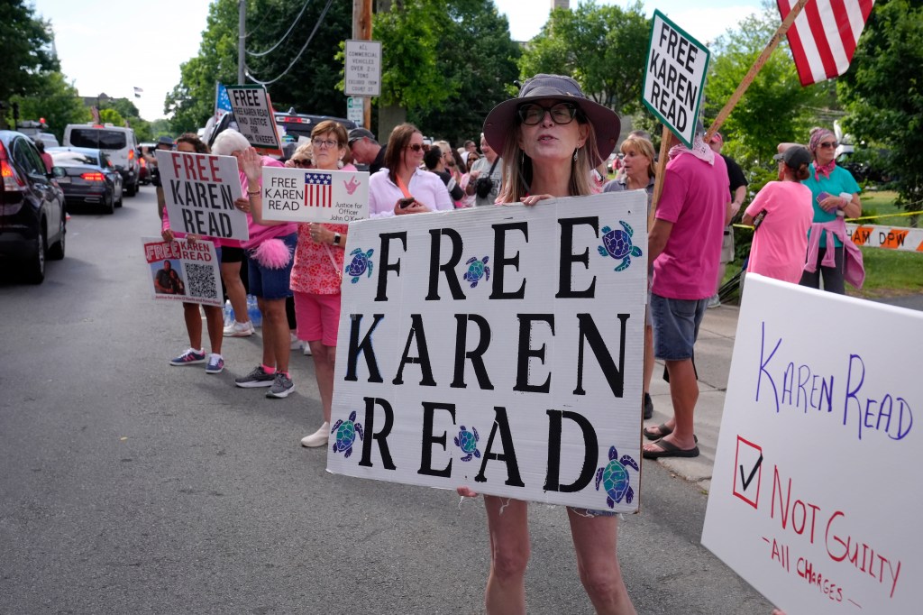 a supporter of Karen Read, displays a sign to passing cars near Norfolk Superior Court