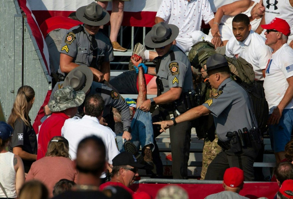 State police officers removing a victim from the stands at the rally.