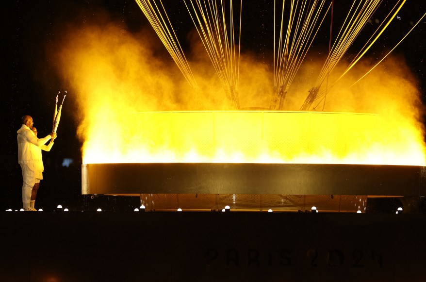 Torchbearers Teddy Riner and Marie-Jose Perec light the Olympic cauldron.