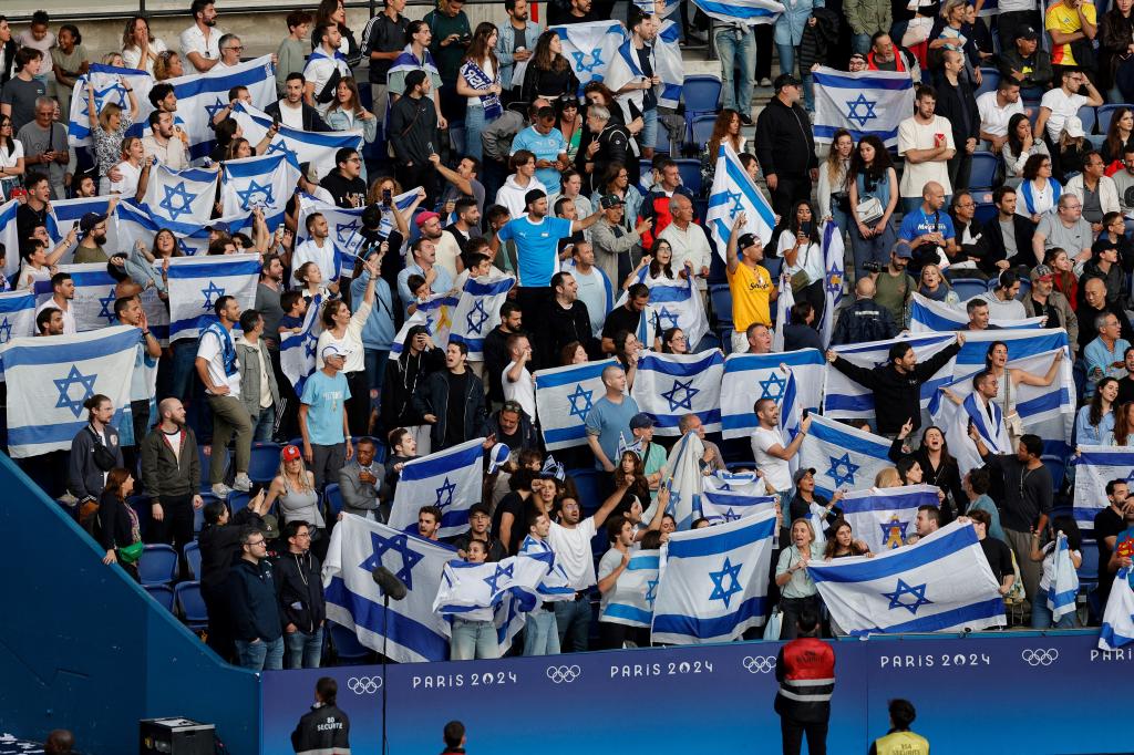 Israel's supporters wave flags in the men's group D football match between Israel and Paraguay during the Paris 2024 Olympic Games at the Parc des Princes in Paris on July 27, 2024. 