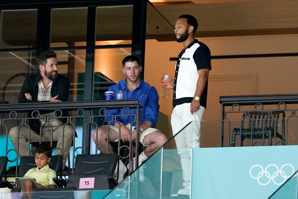 Nick Jonas and John Legend conversing with others while attending the women's artistic gymnastics qualification round at the 2024 Summer Olympics in Paris, France