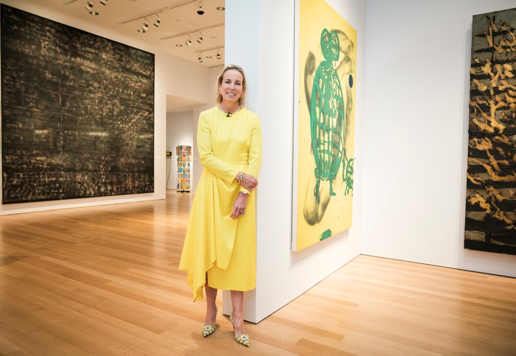 Bonnie Brennan, President of Americas at Christie's auction house in Manhattan NY, in a yellow dress standing in front of a painting