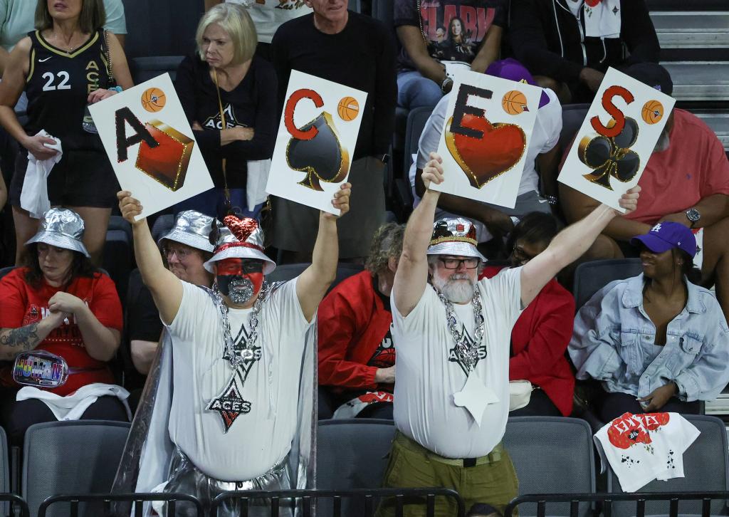 Las Vegas Aces fans Albert Ronquillo (L) and Matt Schafer, both of Nevada, wave playing card-style signs in the fourth quarter of Game One of the 2023 WNBA Playoffs finals between the Aces and the New York Liberty at Michelob ULTRA Arena on October 08, 2023 in Las Vegas, Nevada. The Aces defeated the Liberty 99-82. 