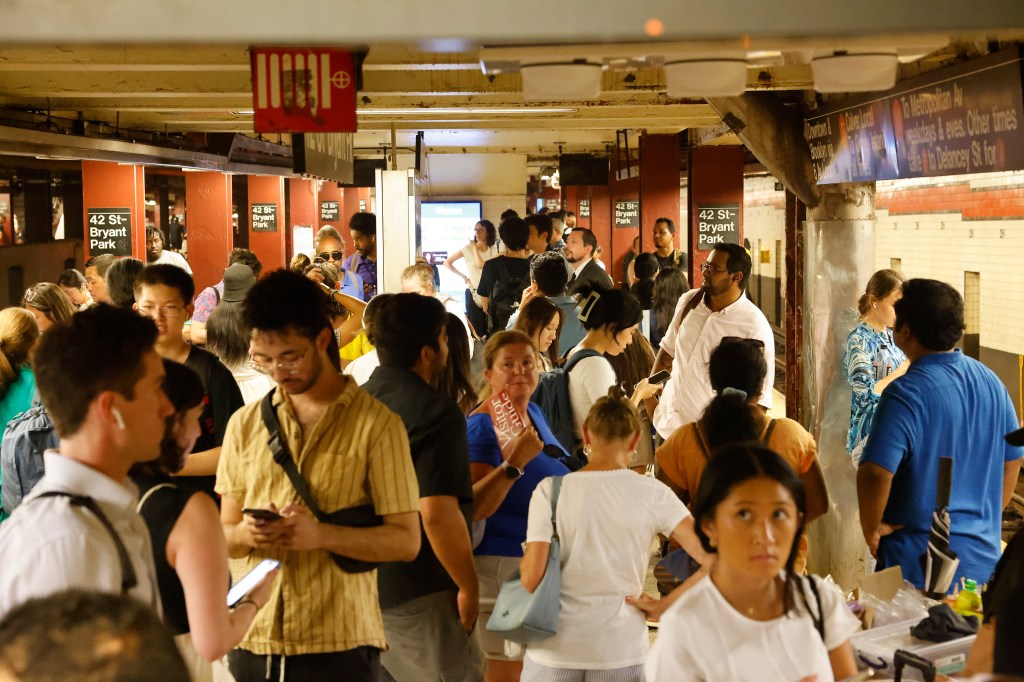 Passengers at the F and 7 train at Bryant Park station suffer through the heat in the NYC subway with the F train down. 