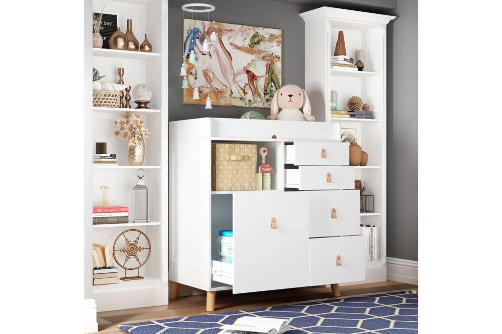 A white dresser with open drawers and toys on top.