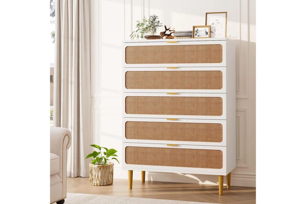 A white and rattan tall dresser in a bedroom.