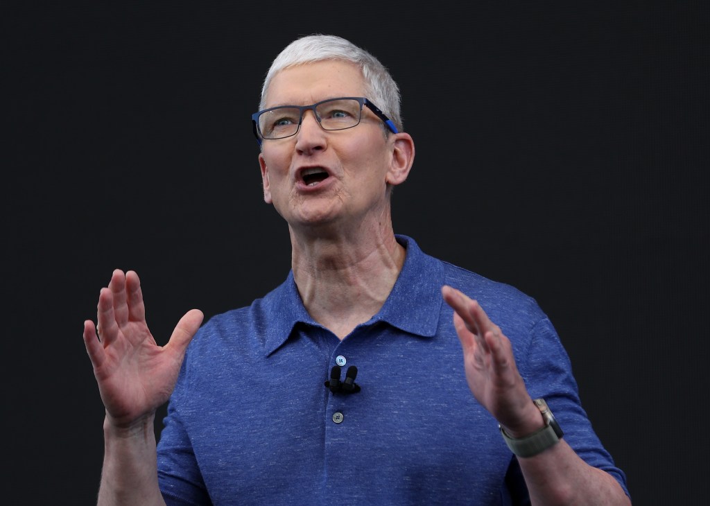 Apple CEO Tim Cook in a blue shirt, delivering remarks at the Apple Worldwide Developers Conference, highlighting incorporation of AI in Apple's future plans.