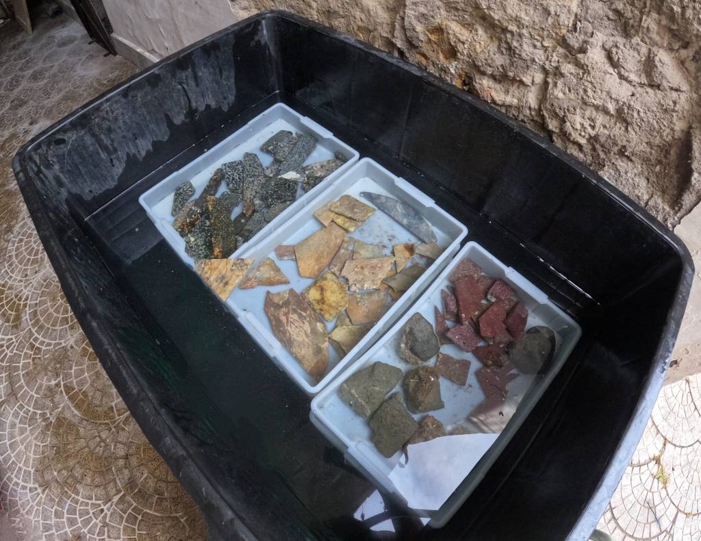 Archaeologists restoring a large, colorful Roman mosaic made of thousands of repurposed marble pieces on the floor of an ancient, submerged villa in Italy