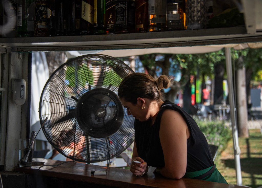 A waitress in Seville cooling herself with a fan at a restaurant during a heatwave on July 23, 2024