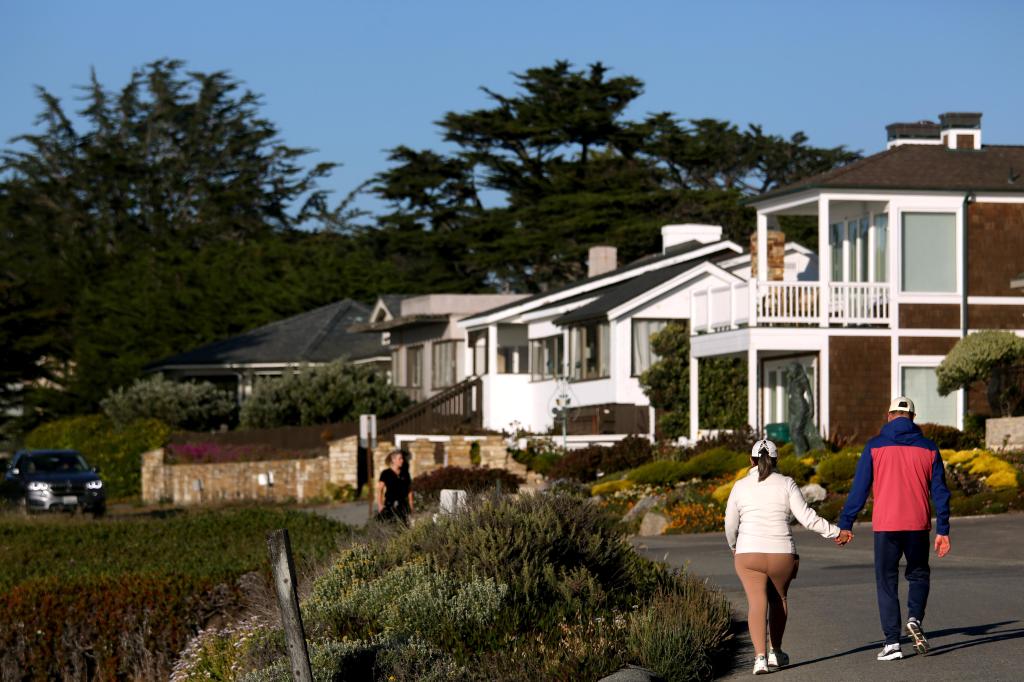 A couple walk along Carmel Beach drive in Carmel-By-The-Sea on June 17, 2024. 