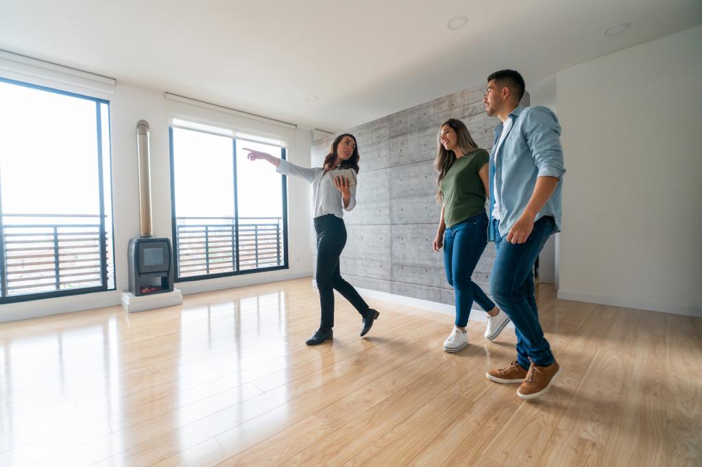 Real estate agent showing a house for sale to a happy couple