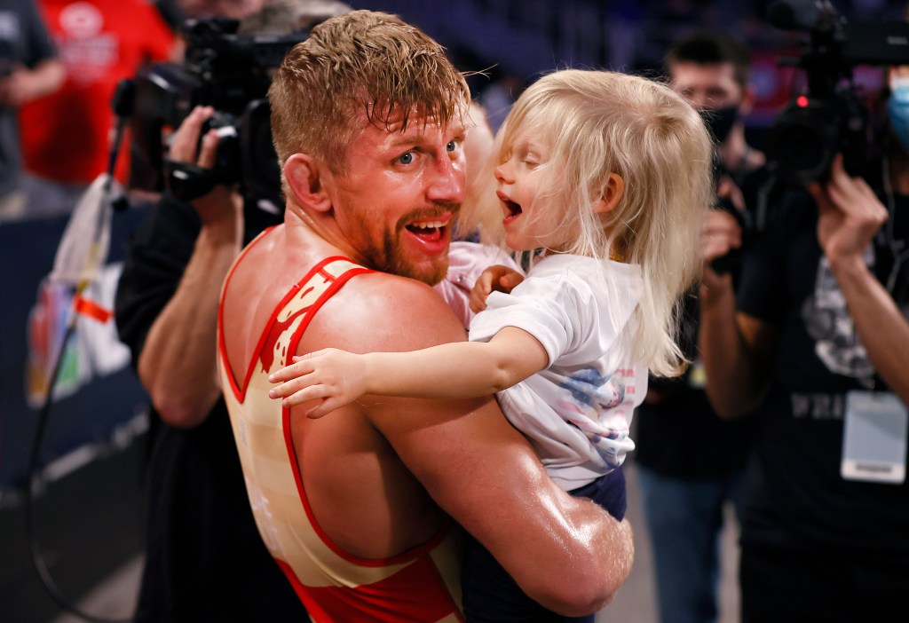 Kyle Dake holding his child, celebrating with family after winning the Freestyle 74kg finals at the U.S. Olympic Wrestling Team Trials