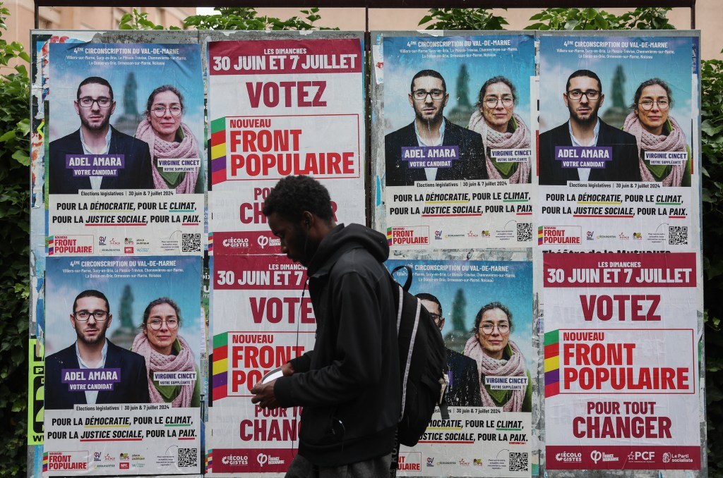 A man walks past election posters in France.