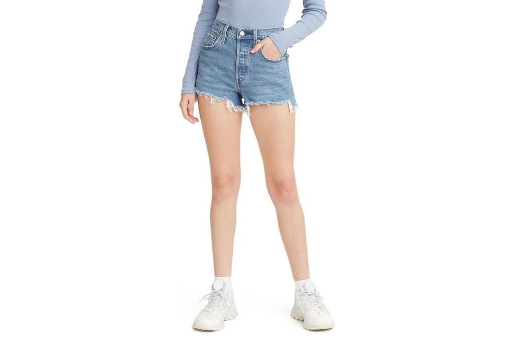 A woman wearing a blue shirt and denim shorts