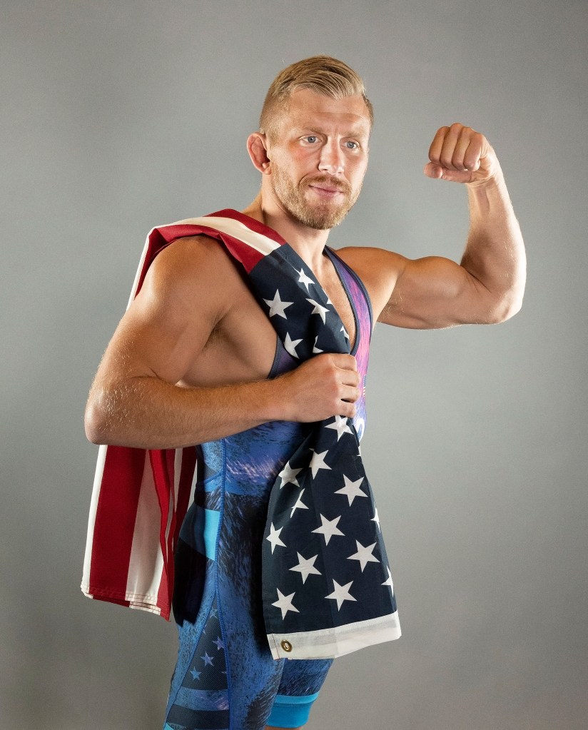 Kyle Dake, male wrestler from USA Olympic Wrestling Team, flexing his arm with a flag at the Media Day in Colorado Springs, 2024