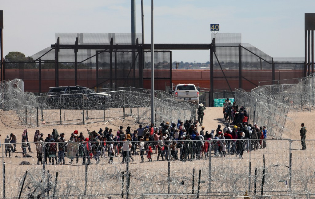 Migrants lining up for transfer by US Border Patrol after crossing Bravo River in El Paso, Texas, viewed from Ciudad Juarez, Mexico