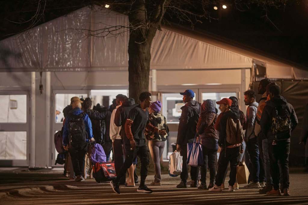 right migrants in the evening line up to enter the shelter