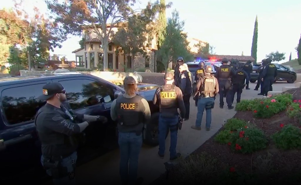 Police officers standing next to a car during a raid on a wealthy mother's mansion with a vineyard