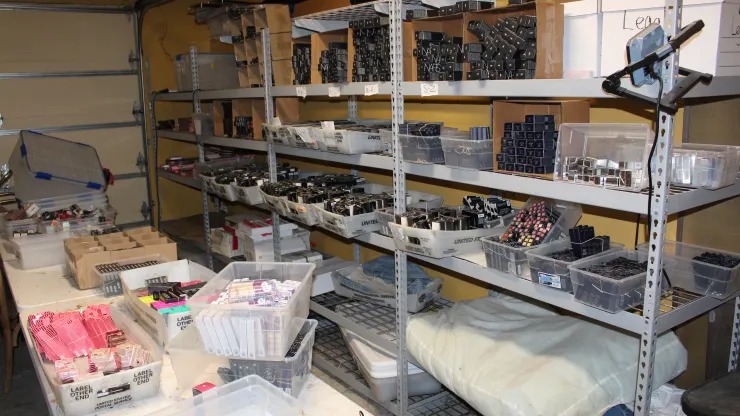 A shelf filled with various boxes of stolen merchandise in the garage of a wealthy mother involved in organized crime