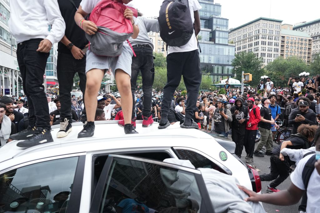 Rioters are seen standing on vehicles amidst Kai Cenat's giveaway at Union Square