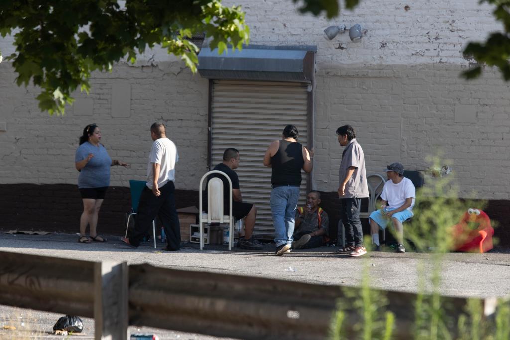 Migrants hang out in a lot behind the closed store in Queens last week. 