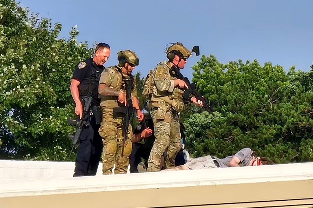 Officers stand over the body of shooter Thomas Matthew Crooks after an assassination attempt on former President Donald Trump during a campaign rally in Butler, PA, Saturday, July 14, 2024.