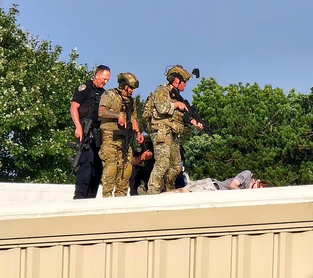 Officers stand over the body of shooter Thomas Matthew Crooks after an assassination attempt on former President Donald Trump during a campaign rally in Butler, PA, Saturday, July 14, 2024.