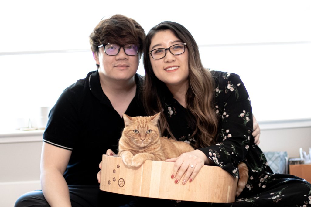 Kathy Guo and Sam Xie with their ginger tabby cat, Waffle, who is making coffee