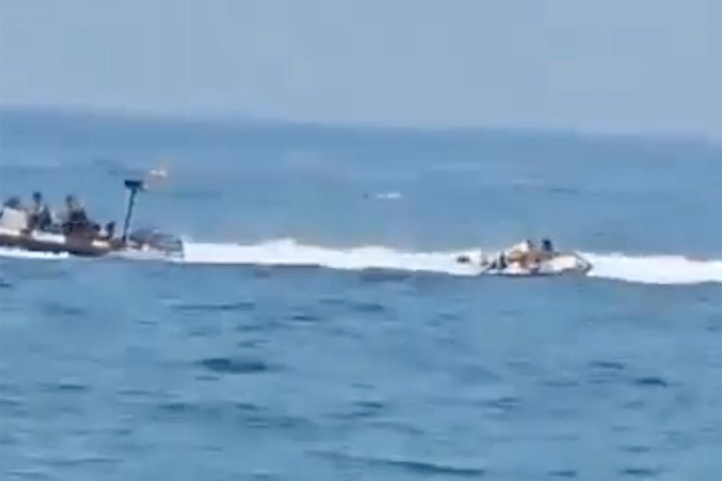 Spanish police boat veering towards a small inflatable dinghy carrying four individuals, resulting in one person falling into water