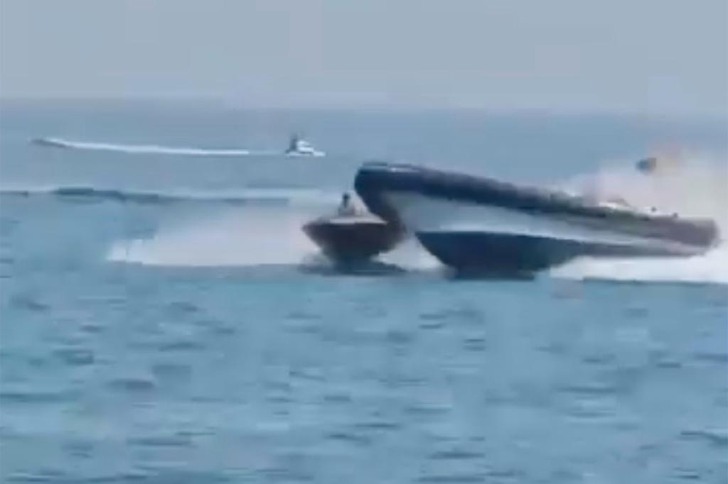 Spanish police boat manoeuvring near a small dinghy with four people on board near the coast of Spain