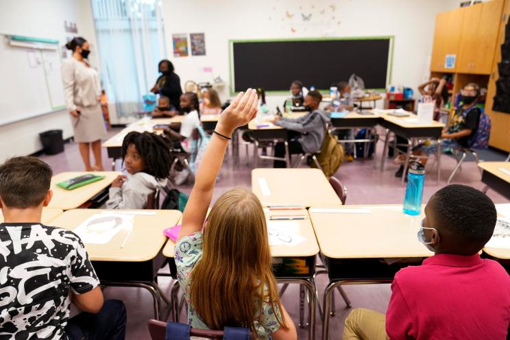 A student raises their hand in a classroom at Tussahaw Elementary school