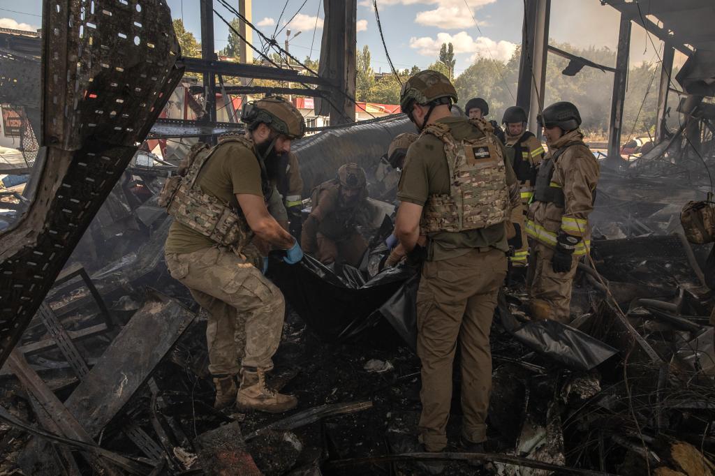 Ukrainian emergency rescue personnel and military members recover the body of a victim from the rubble at the site of the destroyed supermarket following a Russian strike, in Kostyantynivka, eastern Donetsk region, on August 9, 2024