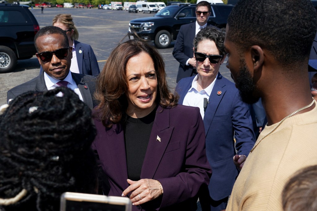 US Vice President Kamala Harris in a purple suit speaking with supporters before boarding Marine Two at Soldier Field landing zone in Chicago, 2024