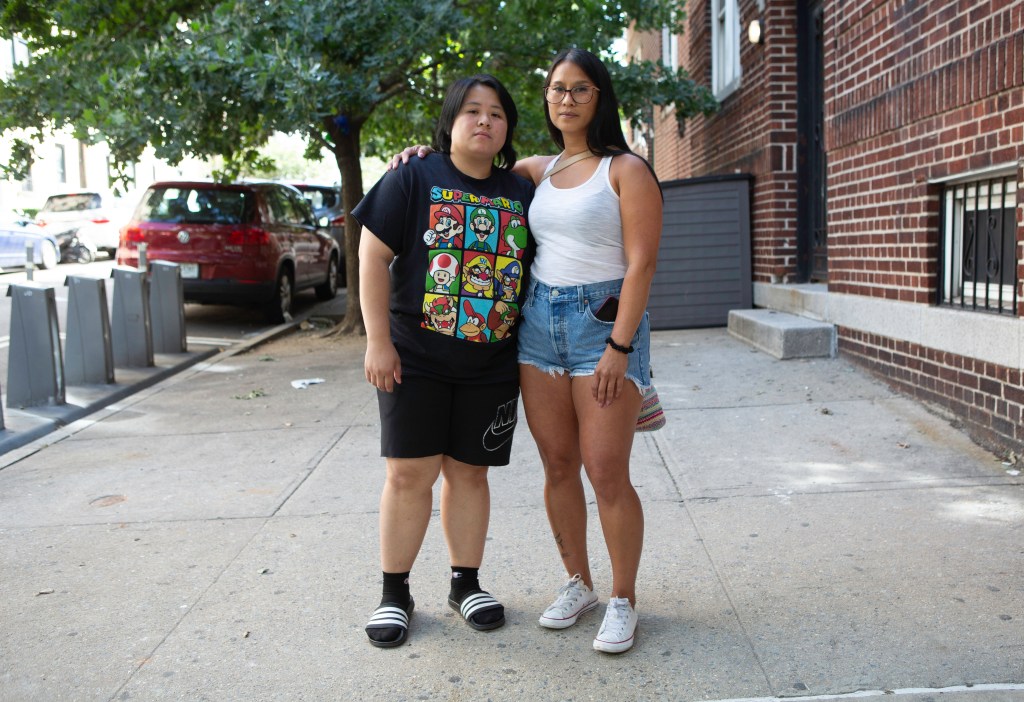 Volunteers Raquel Matuguina and Lia Tracy posing on a sidewalk, involved in the search for missing bodega cat Antonio from the K'Glen Deli & Sari-Sari Store in Queens, 2024.