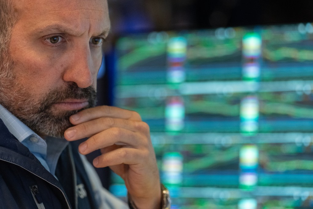 A worried trader working on the floor of the New York Stock Exchange as economic data reveals signs of a weakening economy, causing a significant drop in Dow, S&P 500, and Nasdaq